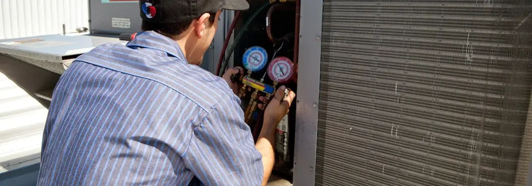 HVAC technician servicing a condenser unit in Carney